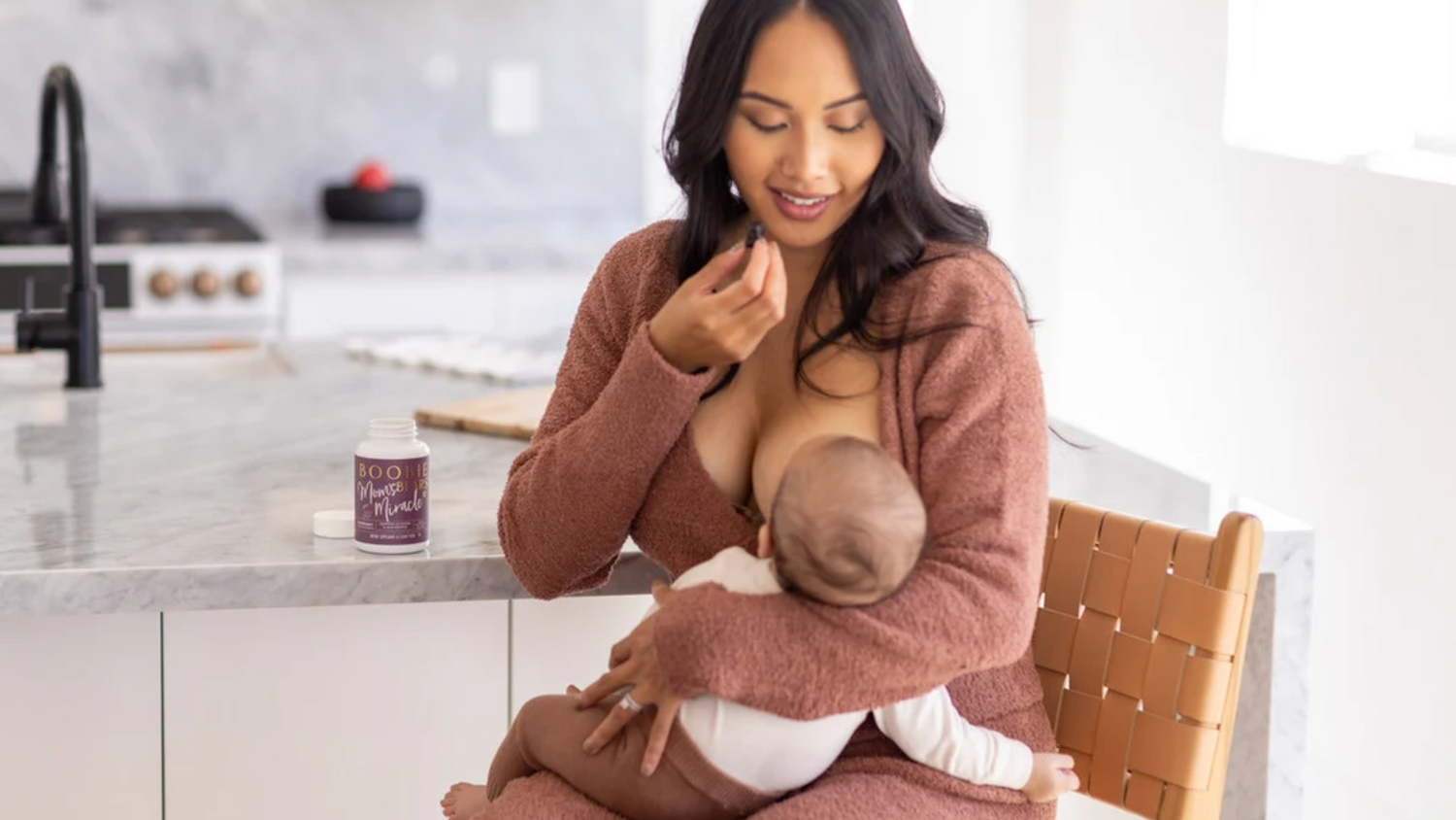 Mom breastfeeding her baby while taking BOOBIE Mom's Miracle supplement gummies.