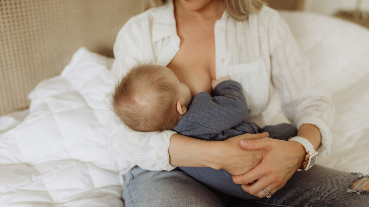 Mother breastfeeding her baby at home, representing the kind of everyday moment an IBCLC helps support.