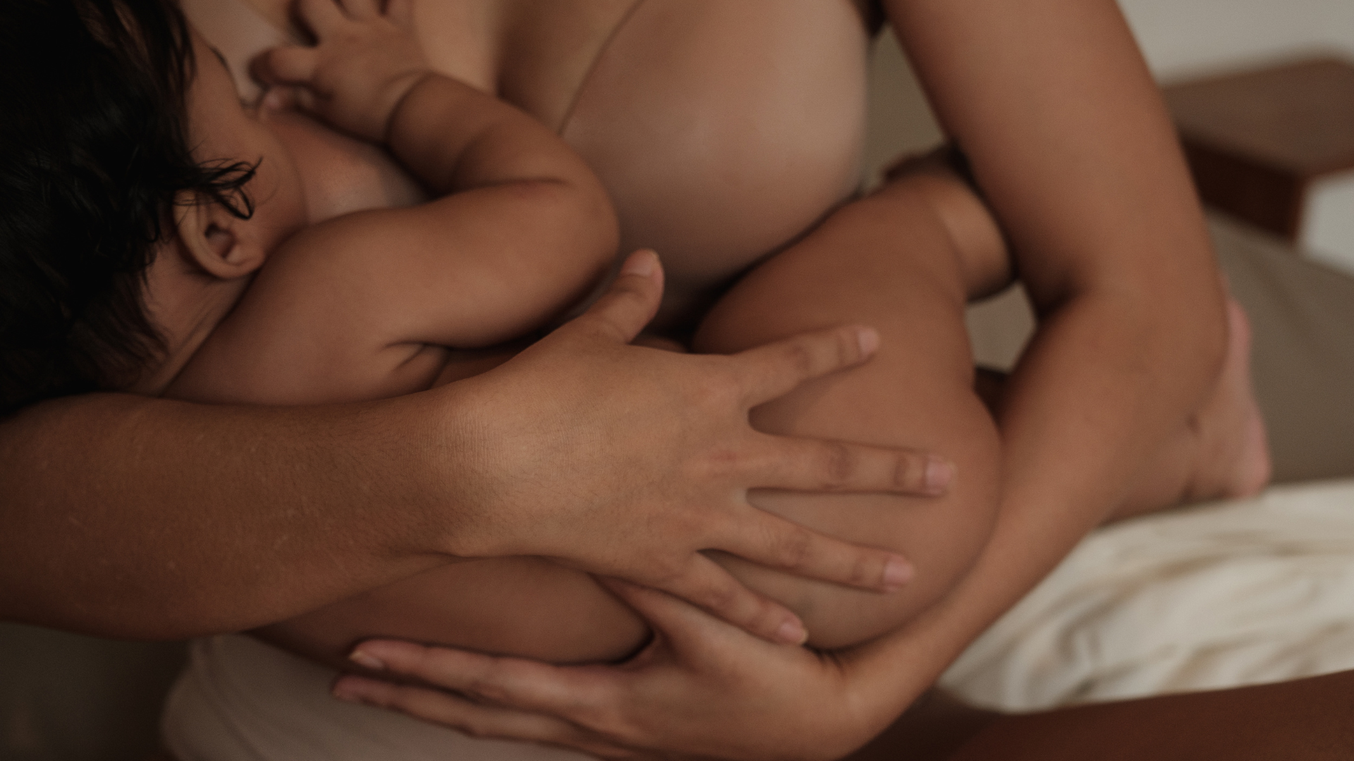 Mother breastfeeding her baby at night in a softly lit room.