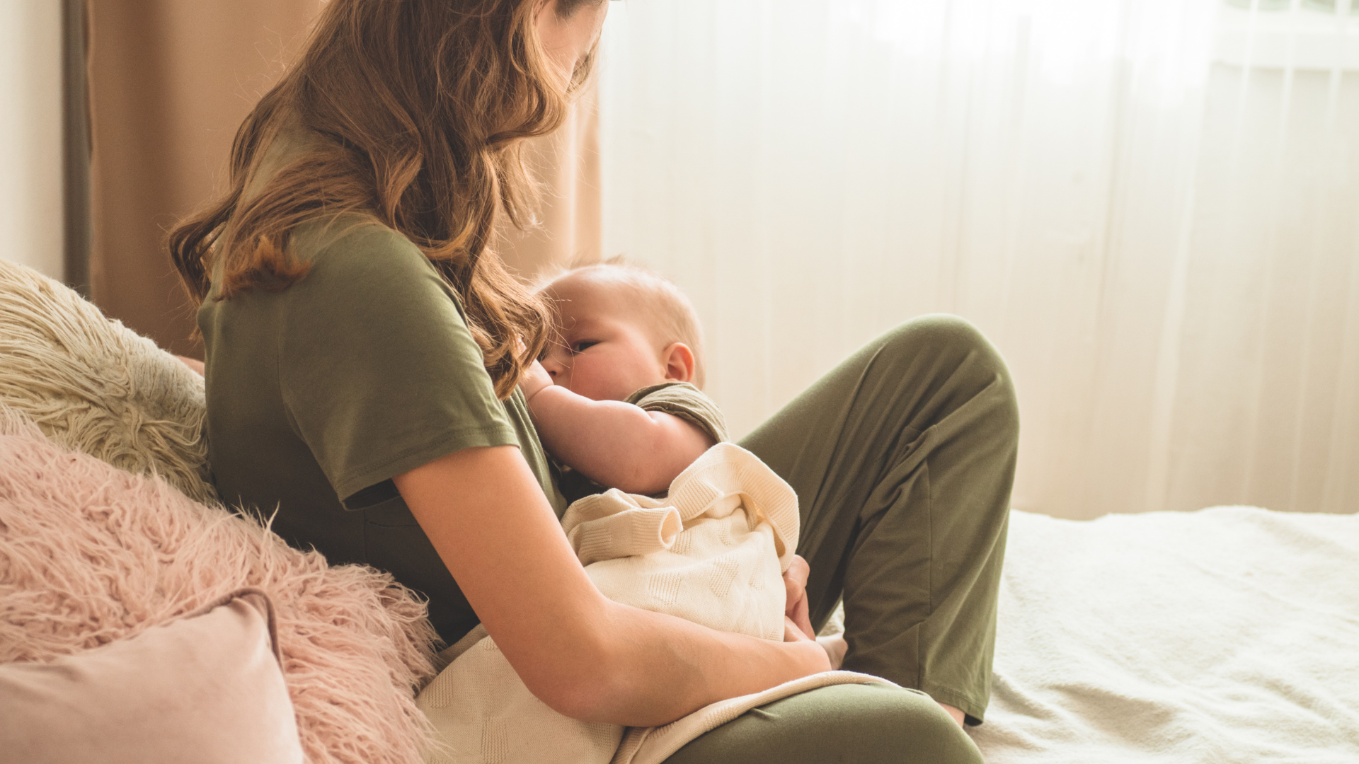 Mother breastfeeding her baby in a cozy, sunlit bedroom while learning tips to increase milk supply.